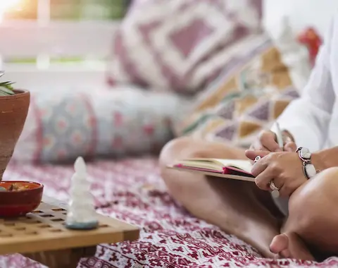 Une personne assise qui écrit sur un cahier.